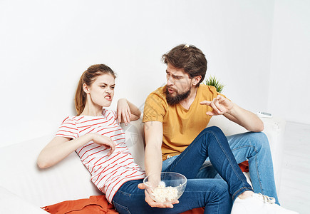 有爆米花的男子和 橙色格子沙发上的女人 家人朋友玩得开心幸福男人妻子控制浪漫房子闲暇女性技术男性互联网高清图片素材