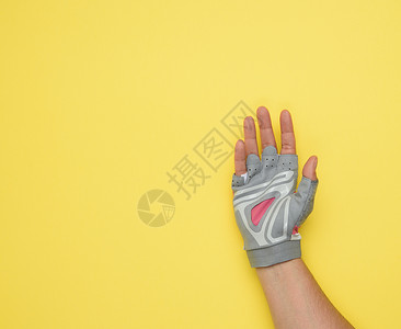 手戴灰色手套的女子 以表彰运动和骑自行车黄色背景的人为荣;背景图片
