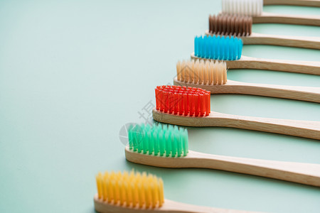 一套由浅绿色背景的竹木制成的环保抗菌牙刷 环保趋势生态木头刷子浴室工具材料口服牙齿彩虹卫生健康高清图片素材