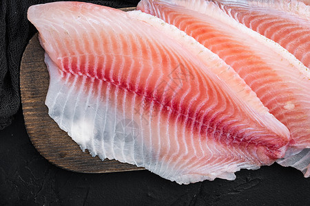黑底海鲜黑底 顶视面的蒂拉皮亚鱼片肉海鲜白鱼粉色背景