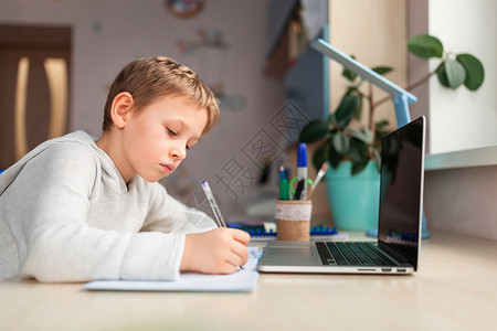 在家做功课时在家学习的可爱小男孩 远程教学在线教育 续写作学校桌子孩子停留研讨会互联网导师班级技术背景图片