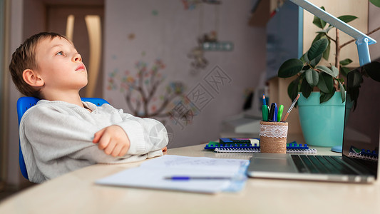 在家做功课时在家学习的可爱小男孩 远程教学在线教育 续停留班级家庭作业职场电脑工具导师写作瞳孔笔记本背景图片