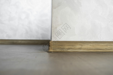 与具有木质纹理的塑料底板层压 家里新安装的强化木地板和踢脚板 现代设计 深色橡木地板镶木地板上塑料底座的特写压板粮食装饰材料硬木背景图片