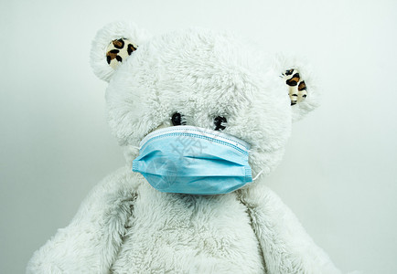 白色背景的蒙面泰迪熊玩具褶皱外科样本防御棉签玩具熊疾病蓝色棉布背景图片