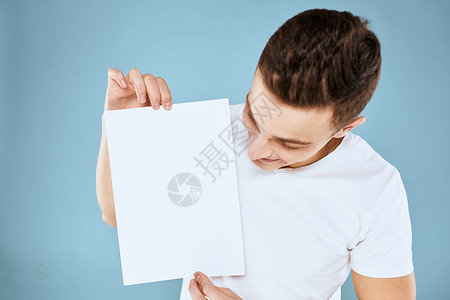 一个穿白色 T 恤的男人手里拿着一张纸 情绪是蓝色背景的裁剪视图 Copy Space人士男性展示商业成人推介会办公室广告牌标语背景图片