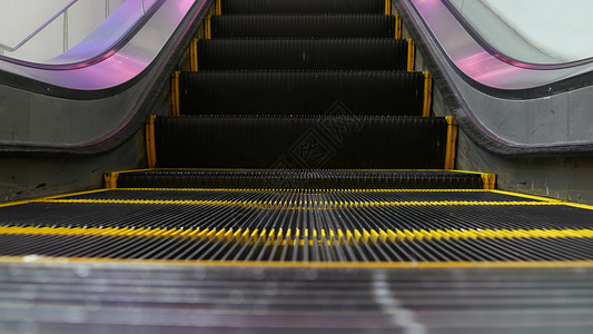 现代自动扶梯楼梯低角度环形透视图 自动电梯机构 楼梯上的黄线被紫光照亮 未来派空机械楼梯直行城市地面循环工程隧道运输基础设施紫色背景图片