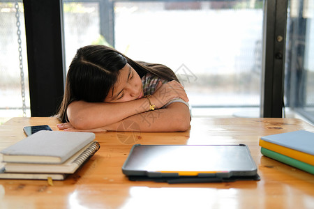 在图书馆深考后睡觉的已累累 精疲力竭的女学生学校睡眠学生学习女孩考试懒惰的高清图片素材