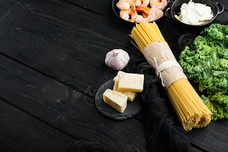 意大利面配料 海鲜意粉 黑色木桌背景上的虾 虾 奶酪 带有复制空间和文本空间背景图片