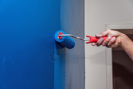 将墙涂成蓝色的工人男人画笔刷子工作装潢师装饰工具色调房子墙纸背景图片