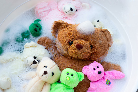肥皂气泡洗衣用洗衣洗涤的水在清洗前溶解时 将软玩具熊放在洗衣液中衣服家务肥皂篮子浴缸盆地搪瓷织物垫圈工作背景