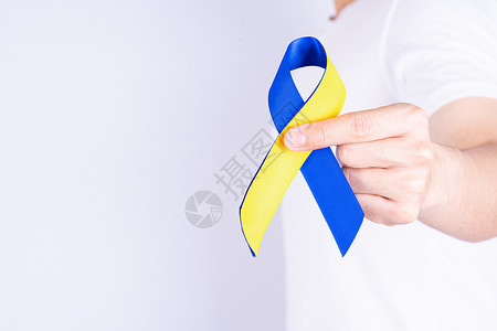 23对染色体Down综合症日 手握蓝黄丝带对胸部支助病人胸腔支持认识的有病残疾患者卫生一体化婴儿活动康复学习海报教育斗争丝带背景