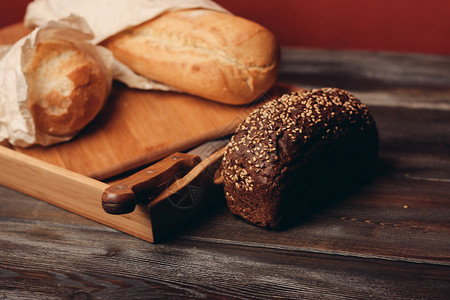 盘子和桌上一把利刃刀上的黑麦面包面粉面包桌子饮食早餐木板乡村健康饮食小麦小吃背景