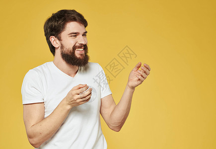 一个男人用双手在黄色背景手势上 胡须上留了胡子年轻的高清图片素材