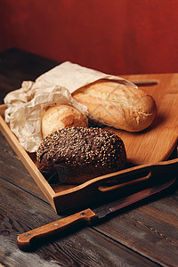 餐盘上的黑麦面包和红背景的桌子上一把利刃刀木板早餐脆皮小麦粮食乡村面包小吃健康饮食农业背景