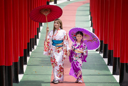撑船赏荷女孩和服中的妇女和小女孩拿着伞走进来 在圣殿红门 在日本花园的红色门艺妓旅游宗教戏服地标女士女孩人行道裙子隧道背景
