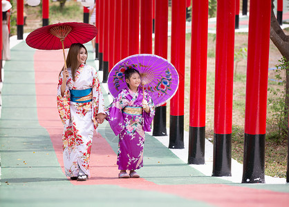 撑船赏荷女孩和服中的妇女和小女孩拿着伞走进来 在圣殿红门 在日本花园的红色门神道女孩旅游人行道裙子宗教戏服地标小路女性背景