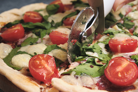 切披萨带奶酪 西红柿 菠菜和香肠的披萨服务树叶美食面团午餐烹饪食物小吃作品桌子背景