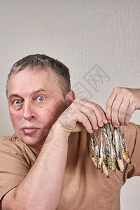 一个男人手里握着许多鱼 咬在骨头上骨骼小吃美食西鲱食物烹饪午餐鳀鱼尾巴油炸背景图片