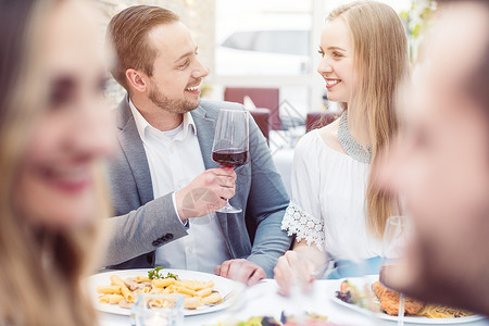 在意大利餐厅享受饮料和食物的愉快的人们在意大利餐馆盘子男朋友女朋友乐趣浪漫夫妻酒精女孩伙伴友谊背景图片