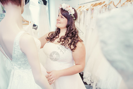 作为新娘 在婚礼店里寻找新娘穿的新娘女郎婚纱乐趣裙子白色女士肥胖女性购物快乐模特儿背景图片