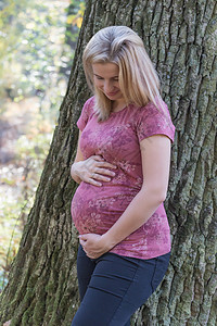 年轻女性怀着怀孕的肚子阳光高清图片素材