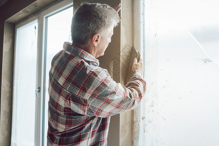 窗口打开时工作的粉碎器工作服劳动瓦工工人涂层窗户绝缘内壁房子石膏背景图片