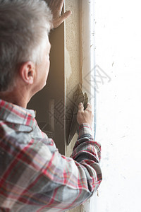 窗口打开时工作的粉碎器泥水匠石膏工作服男人劳动砂浆瓦工工匠水泥职业背景图片