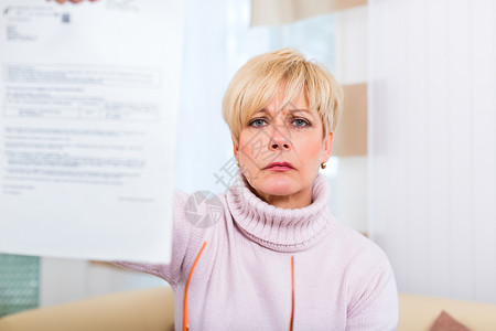 在家的老年人收到一封负面信件女士退休女性沙发房间长椅阅读客厅愤怒背景图片