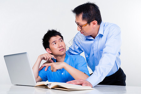 亚裔父亲和儿子在家上学学习教学帮助阅读教科书学生家庭作业作业指导男人专注知识高清图片素材