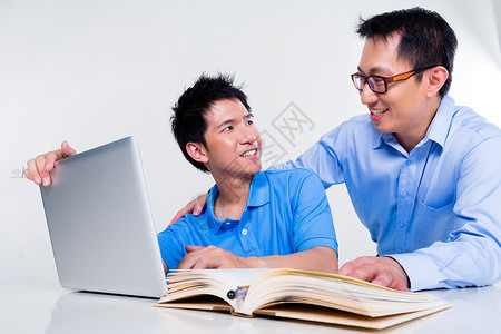 亚裔父亲和儿子在家上学学习男人专注帮助家庭教学家庭作业男生学生指导知识阅读高清图片素材