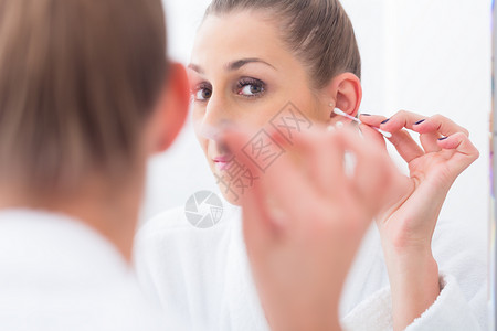 妇女用棉芽洗耳的妇女耳垂浴室耳朵耳垢金发卫生间内耳瓷砖化妆品浴衣背景图片