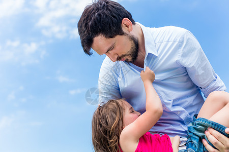 父亲怀着女儿保护她的父亲爸爸孩子蓝色幸福天空拥抱手臂背景图片