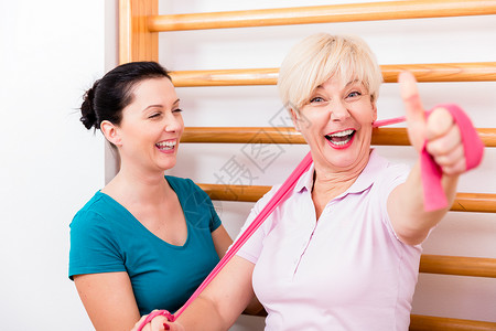 帮助年长妇女在使用电带运动期间的助老妇女背景图片