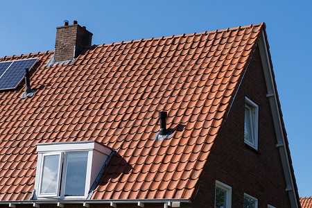 屋顶有红瓦烟囱和太阳能电池板 用于制造可再生能源和清澈的蓝色 sk背景图片