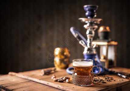 杯子中的黑茶水烟饮料管道持有者木头桌子金属玻璃静物背景图片