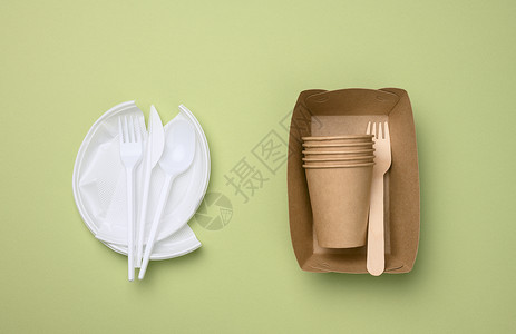 绿色纸来自一次性餐具的不可降解塑料垃圾和一套由环保回收材料制成的餐具背景