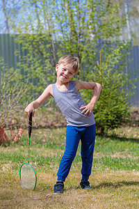 一个白头发的小孩在草坪上玩badbinton游戏微笑喜悦学习婴儿乐趣闲暇罢工幼儿园球拍训练背景图片