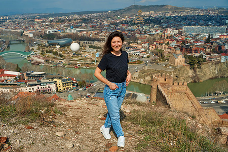 一个可爱的黑发女孩从山丘上 享受着第比利斯的美丽景色 全城都在她脚下蓝色街道市中心堡垒天线建筑中心地标景观天际背景图片
