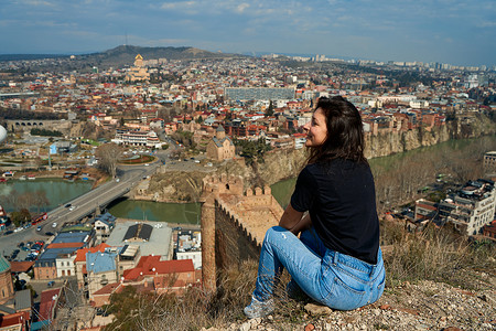 一个可爱的黑发女孩从山丘上 享受着第比利斯的美丽景色 全城都在她脚下历史性建筑天空堡垒旅行大教堂天线地标教会旅游背景图片