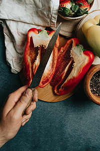 用一把手和一些调味品用半刀切胡椒片 把烹饪桌上的餐桌弄上背景图片