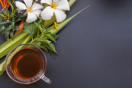 1杯茶和各种花朵 放在黑桌的黑桌子上杯子黑色红色绿色黄花背景图片