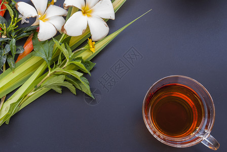 1杯茶和各种花朵 放在黑桌的黑桌子上绿色红色黑色黄花杯子背景图片