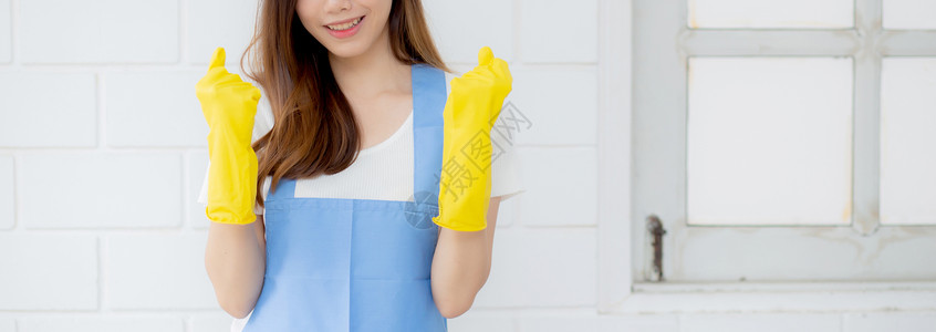 画像中的年轻亚洲女性是戴着橡胶手套和围裙的管家 用于在家保护 女佣制服 清洁和洗涤 女孩站立工人积极 一个人 生活方式概念主妇家成人高清图片素材