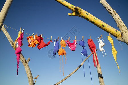 女人的泳衣在免费海滩上烘干自由裙子比基尼洗涤泳装天空蓝色衣绳旅游假期背景图片