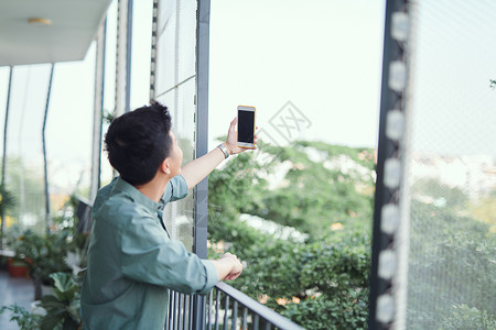 年轻亚洲男子自拍成人阳台白色男人电话男性背景图片