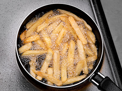 在厨房的电炉上 烤着热油的炸薯条 做自制薯条呢 笑声饮食烹饪脂肪餐厅搅拌土豆芯片钢包电烤箱早餐背景图片