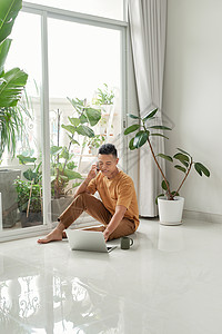 在家聊天的快乐 放松的男人 和检查电子邮件 在笔记本电脑坐在地板上坐着高清图片素材