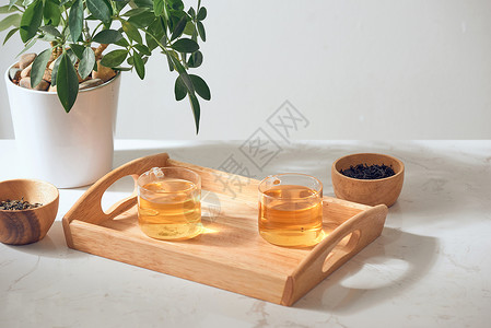 热茶在玻璃杯里 放在木质托盘上早餐植物液体草本植物草本健康杯子绿色橙子药品背景图片