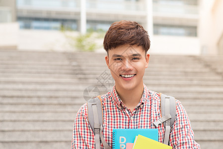 在校园持有书本的大学生学院亚洲裔男学生背包微笑青年教育大学成人男性快乐学校男人西班牙裔高清图片素材