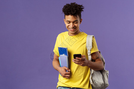 回到学校 大学的概念 帅气的男学生发短信给朋友的肖像 在去校园上课的路上看着手机 拿着笔记本和背包潮人工作情感职业发型工人招聘教背景图片